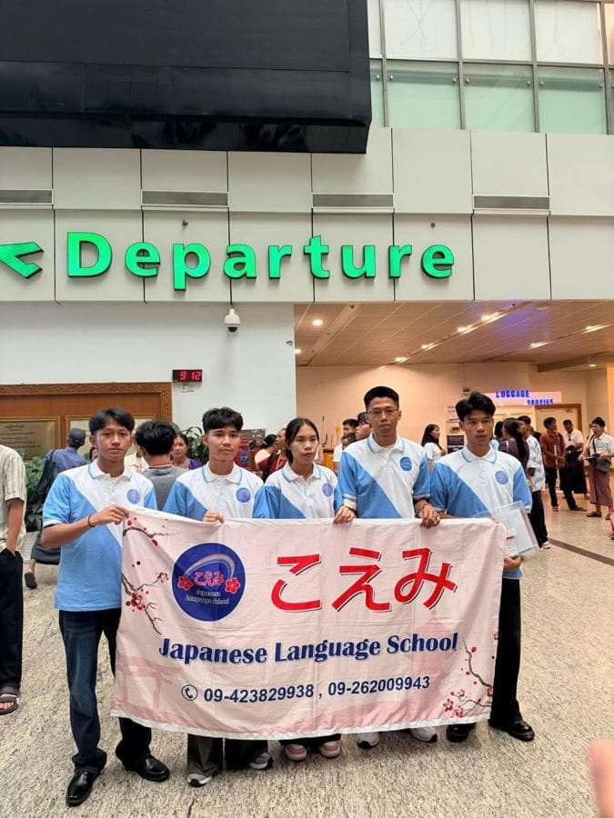 Five students holding the school banner at the airport departure hall