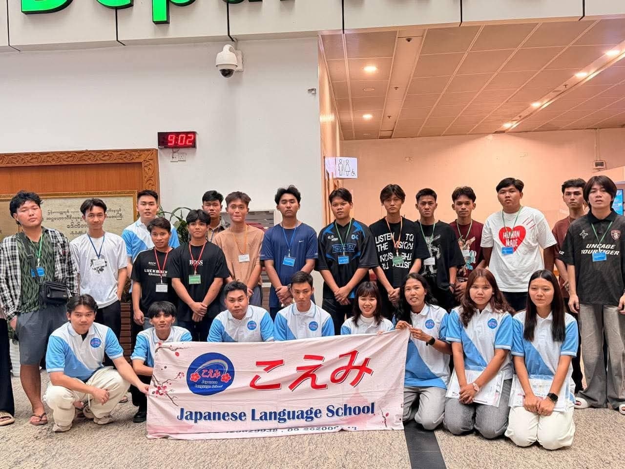 Students and teachers with the school banner at the airport